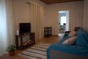 ein Wohnzimmer mit einem blauen Sofa und einem TV in der Unterkunft Casa da Guida in Lajes das Flores