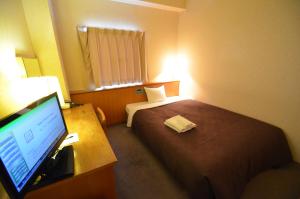ein Hotelzimmer mit einem Bett und einem Schreibtisch mit einem Computer in der Unterkunft Select Inn Nagoya Iwakura Eki-mae in Iwakura