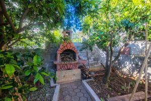 un horno de ladrillo en un jardín con árboles en Apartments Vinka en Trogir