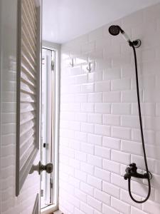 y baño con ducha y pared de azulejos blancos. en Cong Sen Backpackers Hostel en Taitung