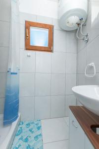ein Bad mit einem Waschbecken und einer Dusche mit einem Fenster in der Unterkunft Apartment Island Dream in Krapanj
