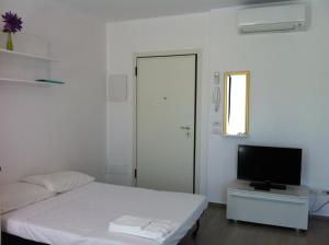 a white room with a bed and a television at Residence Fanny in Rimini