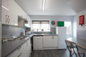 a kitchen with white cabinets and a white refrigerator at Fàilte Mhòr in Fort William