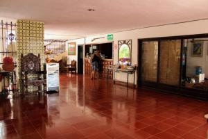 una persona in piedi in una stanza con pavimento piastrellato rosso di Hotel San Clemente a Valladolid