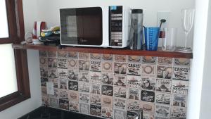 een magnetron die op een plank staat met een betegelde muur bij Pousada Jeito Bom de Viver in Caraíva +17 foto's
