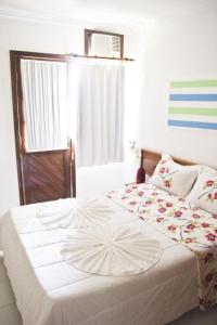 Un dormitorio con una gran cama blanca con flores. en Residencial JERUSALEM 1, en Porto Seguro