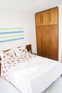 1 dormitorio con cama blanca y armario de madera en Residencial JERUSALEM 1, en Porto Seguro