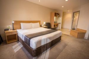 a bedroom with a large bed with a desk and a kitchen at President Hotel Auckland in Auckland