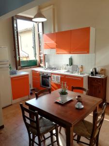une cuisine avec une table en bois, des chaises et des armoires orange dans l'établissement Villino Chianti, à Cavriglia