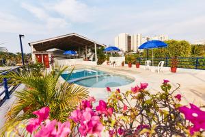 a swimming pool with blue umbrellas and pink flowers at Hotel Suites Ixtapa Plaza in Ixtapa
