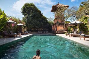 a woman sitting in the water in a swimming pool at The Pavilions Bali - CHSE Certified in Sanur