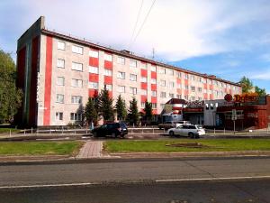 a large building with cars parked in a parking lot at Hotel Kolos in Barnaul