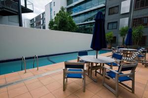 a table and chairs with an umbrella next to a pool at QV Stylish Waterfront Apartment - 317 in Auckland