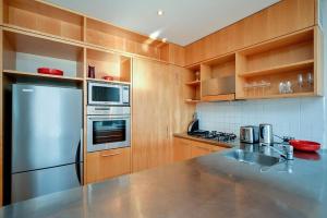 a kitchen with wooden cabinets and a stainless steel refrigerator at QV Stylish Waterfront Apartment - 317 in Auckland