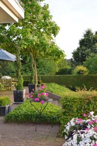 a garden with pink and white flowers and a tree at B&B De Rozenhorst in Baarlo