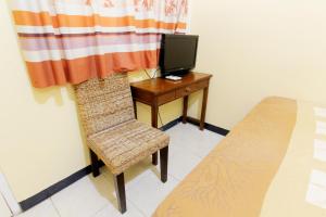 una camera da letto con un letto e una scrivania con una televisione di JJ House Gejayan a Yogyakarta