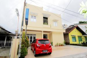 una macchina rossa parcheggiata di fronte a una casa di JJ House Gejayan a Yogyakarta