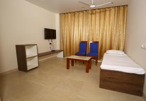 a bedroom with two blue chairs and a bed and a table at Hotel Manbhavan in Mathura