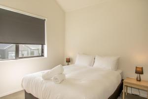 a white bed in a room with a window at Cherry Apartment in Queenstown