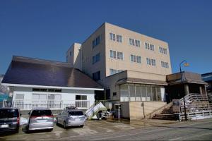 un edificio con coches estacionados frente a él en Hotel Yuzawa Yuzawa Denkiya en Yuzawa