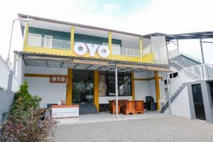 OYO 894 Nusa Indah Homestay Syariah في باتو: مبنى اصفر وبيض مع وجود علامة وفو عليه