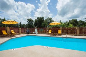 a swimming pool with two umbrellas and chairs and a table at Days Inn by Wyndham Lake City in Lake City