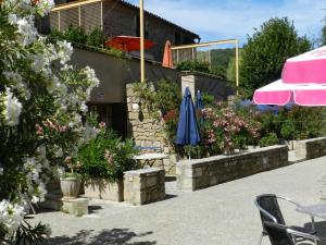 un patio con mesa, sombrilla y flores en Domaine de La Tour, en Salavas