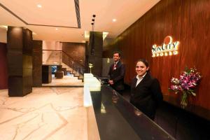 a man and woman standing at a counter in a hotel lobby at Hotel Suncity Apollo, Colaba in Mumbai