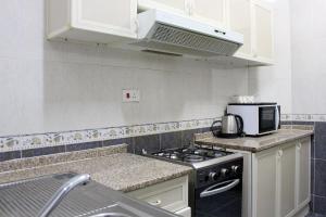a kitchen with a stove and a microwave at Sahara Hotel Apartments in Muscat