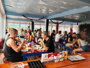 Vang Vieng Freedom View Hostel في فانغ فينغ: مجموعة من الناس يجلسون على الطاولات يأكلون الطعام