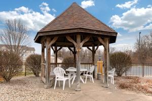 a wooden gazebo with a table and white chairs at Comfort Suites Lafayette University Area in Lafayette