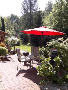 Un patio con una mesa y una sombrilla roja. en Ferienwohnung Am Rauenstein, en Struppen