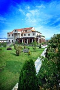 una casa grande con un patio con césped y árboles en Hotel Aria en Podgorica