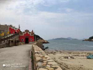 un edificio rojo en la orilla de un cuerpo de agua en Simple life hostel en Nangan