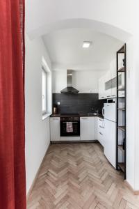 a kitchen with white cabinets and a wooden floor at Apartment Gondola in Maribor