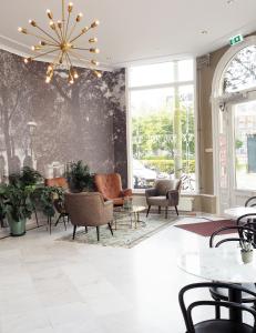 - un hall avec des chaises, des tables et un lustre dans l'établissement Hotel Sebel, à La Haye