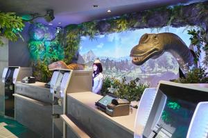 a dinosaur model in a room with a woman at Henn na Hotel Tokyo Haneda in Tokyo