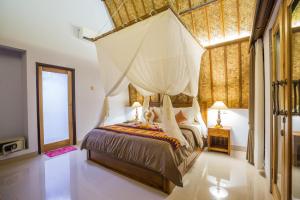 a bedroom with a canopy bed with a mosquito net at Bintang Penida Resort in Nusa Penida