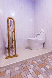 a bathroom with a toilet in a white tiled room at Bintang Penida Resort in Nusa Penida