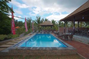 a swimming pool with a gazebo and tables and chairs at Bintang Penida Resort in Nusa Penida