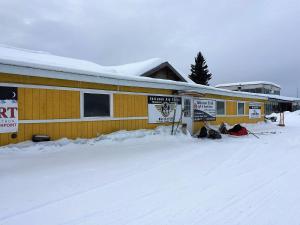 un edificio con dei cartelli sopra nella neve di McGrath Roadhouse a McGrath