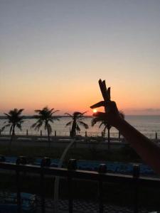 a sunset over the beach with palm trees at White Sand Homestay in Hualien City