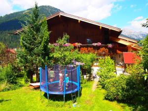 eine Familie, die auf einem Trampolin vor einem Haus spielt in der Unterkunft Appartment Kainhofer in Sankt Martin am Tennengebirge