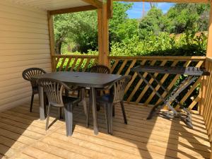 a table and chairs on the back porch of a cabin at Camping Manaysse in Moustiers-Sainte-Marie