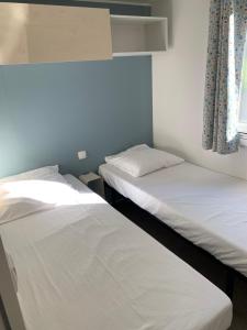 two twin beds in a room with a window at Camping Manaysse in Moustiers-Sainte-Marie