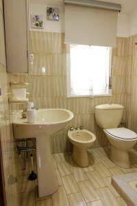 uma casa de banho com um lavatório, um WC e uma janela. em Villetta sul mare in residence em Brucoli