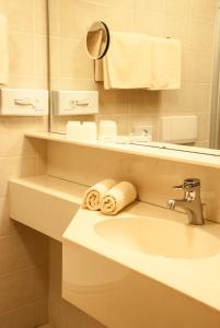 a bathroom with a sink and a mirror and towels at Hotel Garni Romantica in Jerzens