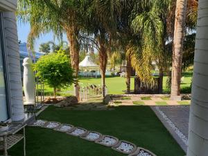 un patio con césped con palmeras y un jardín en Belurana River Manor, en Upington