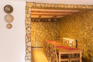 a dining room with a stone wall with a table and chairs at Pensiunea Colt de Munte in Corbeni