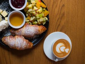 a plate of food with fruit and a cup of coffee at Fama Residence Gdańsk Old Town in Gdańsk
